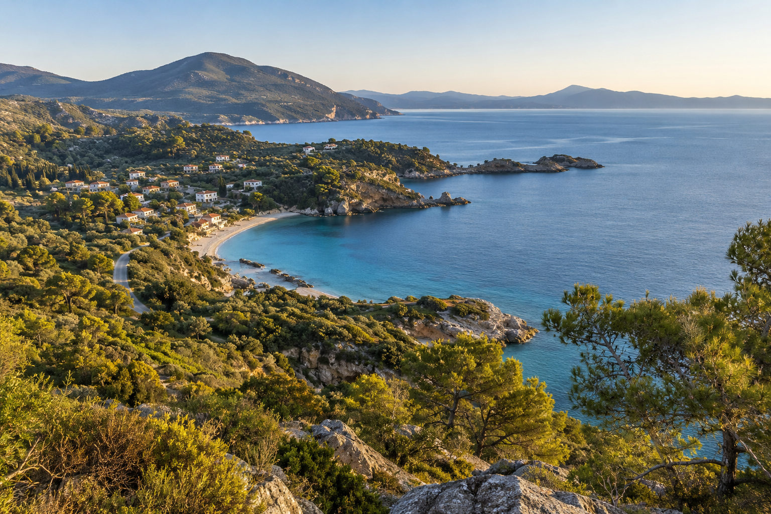 A coastal village beside a bay and green hills.